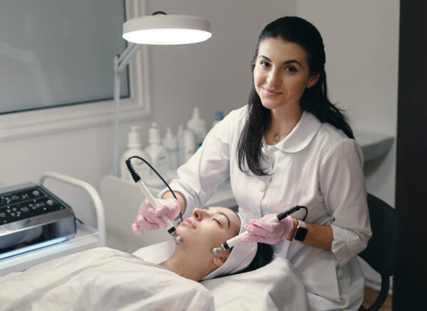 Rejuvenating facial treatment Model with closed eyes and hand's of doctor. Rejuvenating facial treatment. Model getting lifting therapy massage in a beauty SPA salon. Cosmetological clinic, procedure.